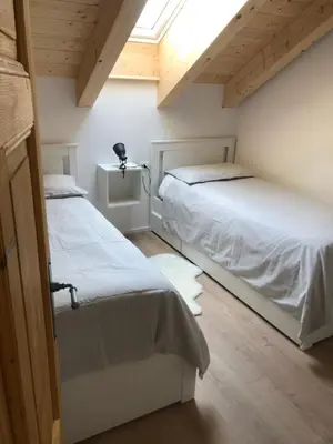 two beds in a room with a window at Piano C Apartment in Cavalese