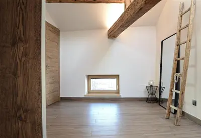 a room with white walls and a wooden floor and a ladder at Apartment El Molin - Alpe Cermis Dolomites in Cavalese