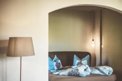 a room with a bed with pillows and a lamp at Bäcksteinerhof in Merano
