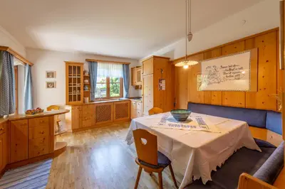 a dining room with a table and a kitchen at Haus Bellutti in Termeno