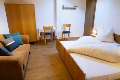 a hotel room with two beds and a couch at Haus Pfalzen - Casa Falzes in Falzes