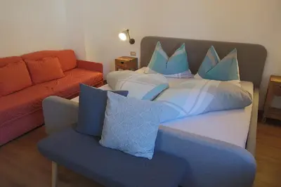 a living room with a couch and a bed with pillows at Haus Pfalzen - Casa Falzes in Falzes