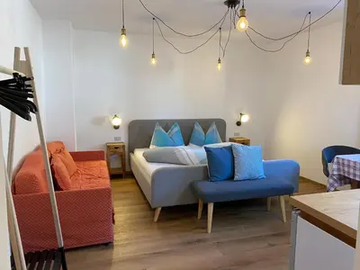 a bedroom with a bed with blue pillows and a chair at Haus Pfalzen - Casa Falzes in Falzes