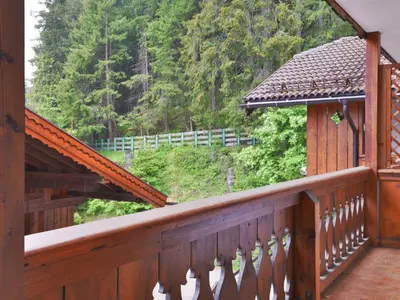 a wooden balcony with a view of a forest at Apartment Villaggio Ladino by Interhome in Mazzin