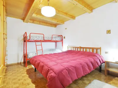 a bedroom with a bunk bed with a red bedspread at Apartment Villaggio Ladino by Interhome in Mazzin