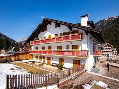 a white building with red windows and a fence at Apartment Ciampac by Interhome in Alba di Canazei