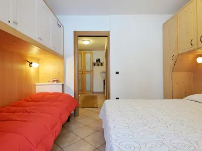 a bedroom with a bed with a wooden wall at Apartment Condominio al Parco-4 by Interhome in Canazei