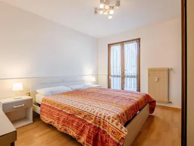 a bedroom with a large bed and a window at Apartment Condominio al Parco-5 by Interhome in Canazei