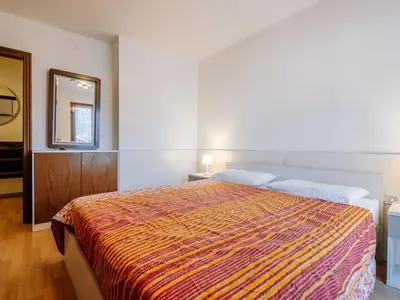 a bedroom with a large bed and a mirror at Apartment Condominio al Parco-5 by Interhome in Canazei