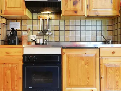 a kitchen with wooden cabinets and a black oven at Apartment Apt 3 by Interhome in Penia