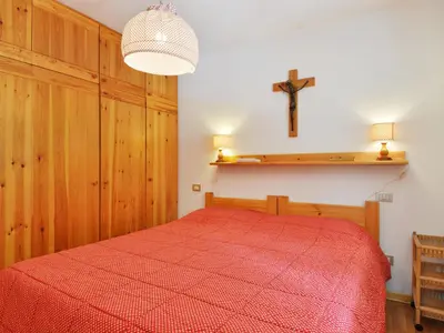 a bedroom with a red bed and a cross on the wall at Apartment Apt 3 by Interhome in Penia