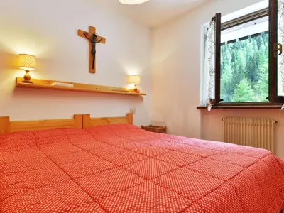 a bedroom with a red bed and a cross on the wall at Apartment Apt 3 by Interhome in Penia
