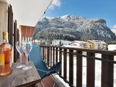 a table with wine glasses on a balcony with a mountain at Apartment Condominio al Parco-1 by Interhome in Canazei