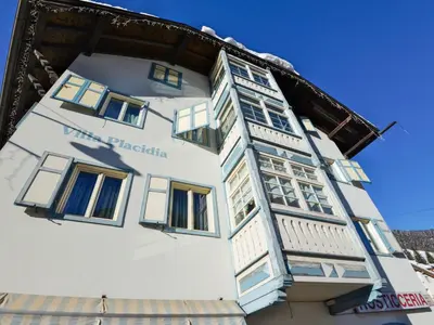 a white building with blue and white windows at Apartment Villa Placidia Apt 24 by Interhome in Campitello di Fassa