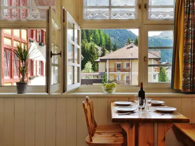 a table with a bottle of wine in a room with windows at Apartment Villa Placidia Apt 24 by Interhome in Campitello di Fassa