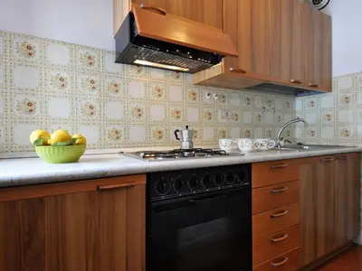 a kitchen with a black stove and a bowl of fruit at Apartment Des Alpes-15 by Interhome in Canazei