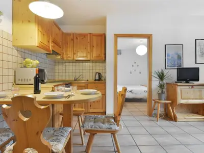 a kitchen with wooden cabinets and a table and chairs at Apartment Apt 2 by Interhome in Canazei