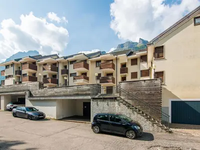 a building with two cars parked in a parking lot at Apartment Enrosadira-4 by Interhome in Alba di Canazei
