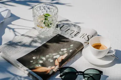 a newspaper with a cup of coffee and a vase at Das Hallinger am Waidmannhof in Merano