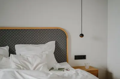 a bed with white sheets and a black and white headboard at Das Hallinger am Waidmannhof in Merano