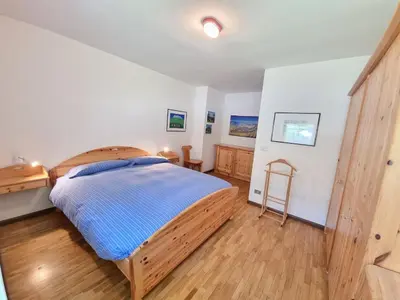 a bedroom with a large bed with a wooden floor at NEGRITELLA in Alba di Canazei
