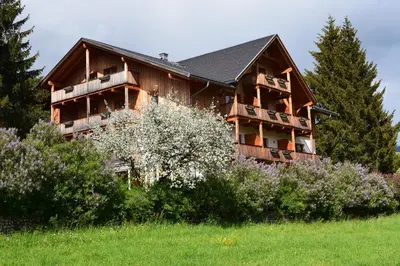 a large wooden house with balconies and trees at Garni Appartments Helvetia in Villabassa