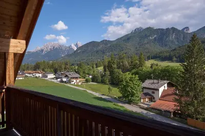 a balcony with a view of a village and mountains at Garni Appartments Helvetia in Villabassa