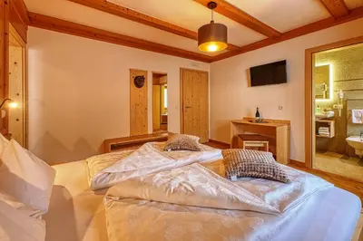 a bedroom with a large bed and a bathroom at Garni Appartments Helvetia in Villabassa