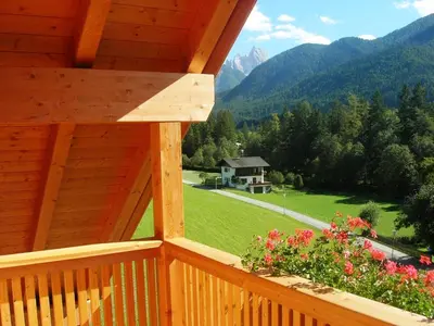 a wooden balcony with a view of a house and mountains at Appartments Helvetia in Villabassa