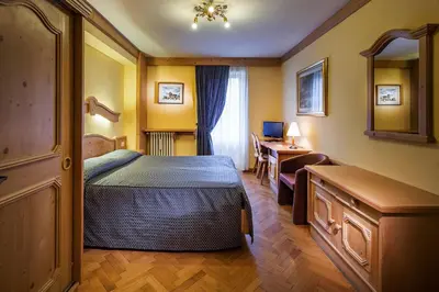 a bedroom with a bed and a desk and a table at Hotel Corona in Cortina dʼAmpezzo