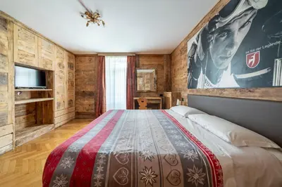 a bedroom with a large bed and a tv at Hotel Corona in Cortina dʼAmpezzo