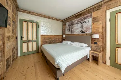 a bedroom with a bed in a room with wooden walls at Hotel Corona in Cortina dʼAmpezzo
