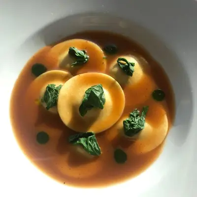 a white bowl of soup with vegetables in it at Ciampedie Luxury Alpine Spa Hotel in Vigo di Fassa