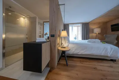 a bedroom with a bed and a table with a lamp at Ciampedie Luxury Alpine Spa Hotel in Vigo di Fassa
