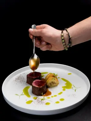 a person holding a spoon over a plate of food at Ciampedie Luxury Alpine Spa Hotel in Vigo di Fassa