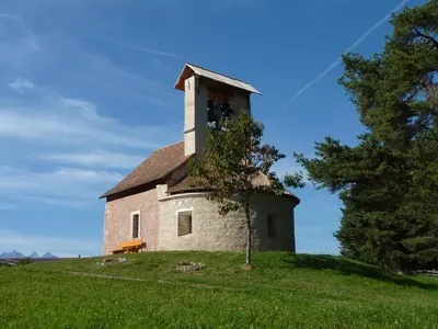 an old church on top of a grassy hill at Gasthof St. Ulrich in Meltina