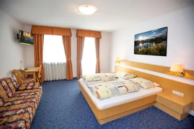 a hotel room with a bed and a couch at Gasthof St. Ulrich in Meltina
