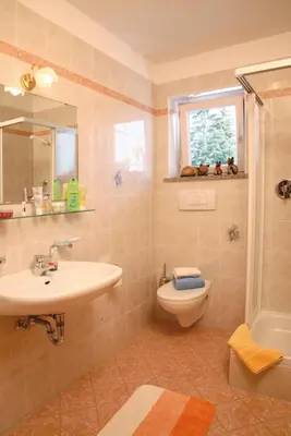 a bathroom with a sink and a toilet and a window at Gasthof St. Ulrich in Meltina