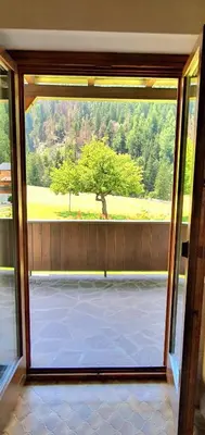 a large window in a room with a view of a tree at Ciasa Confolia in San Vigilio Di Marebbe