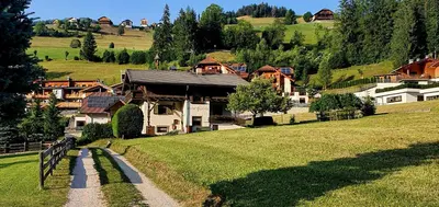 a village on a grassy hill with a house at Ciasa Confolia in San Vigilio Di Marebbe
