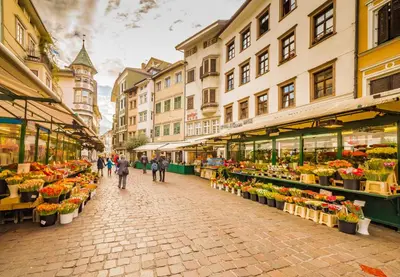 a group of people walking through a flower market at Vinci16 in Bolzano