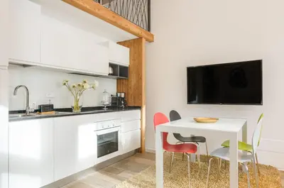a kitchen with a white table and chairs and a tv at Vinci16 in Bolzano