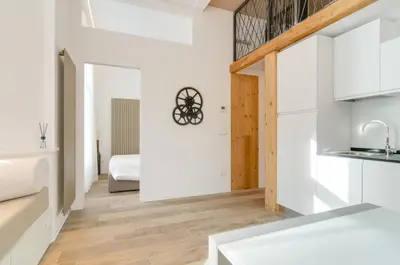 a kitchen with white walls and wooden floors at Vinci16 in Bolzano