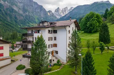 a building in a valley with mountains in the background at Suite Marangon in Falcade