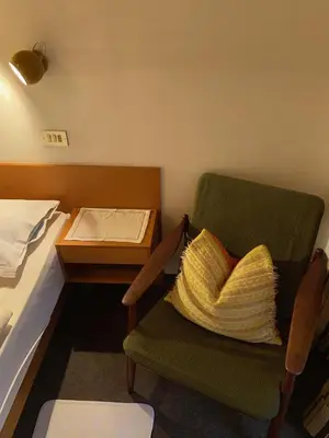 a bedroom with a bed and a chair with a pillow at Gasthof Albergo Ressmair in Merano