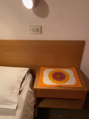 a bed with a wooden table with a flower on it at Gasthof Albergo Ressmair in Merano
