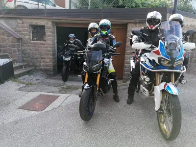 three people on motorcycles parked in front of a garage at B&B SEGONZANO in Segonzano