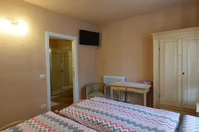a bedroom with a bed and a table and a bathroom at B&B SEGONZANO in Segonzano
