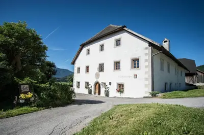 a white building on a road next to a street at Hofbauer in Brunico