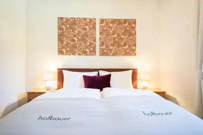 a bedroom with a large white bed with two lamps at Hofbauer in Brunico